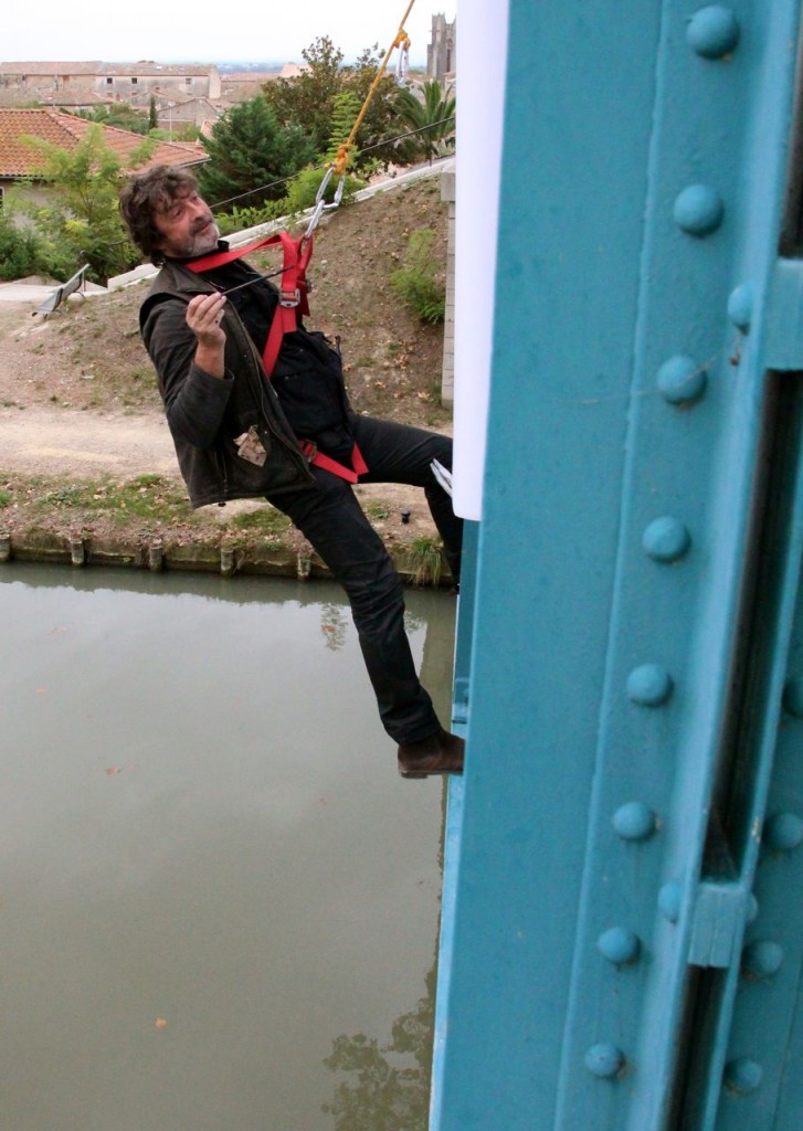Gauthier hangs panels on the bridge in Capestang, painting, bringing awareness to the plight of the planes